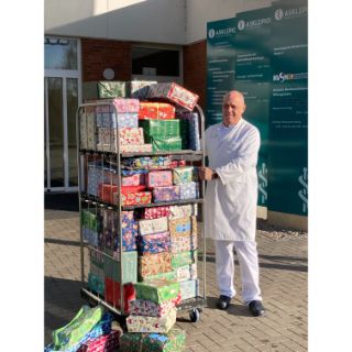 Das Bild zeigt den Ärztlichen Direktor PD Dr. Ralph Tölg mit einem Wagen voller Weihnachtsgeschenke