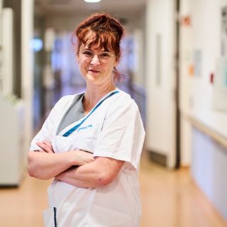 Das Bild zeigt eine Pflegefachkraft in einem Stationsflur stehen. 