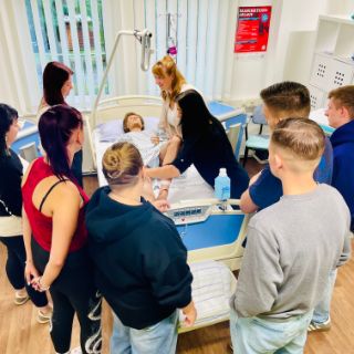 zukünftige Pflegefachkräfte üben für ihre Arbeit am Patientenbett