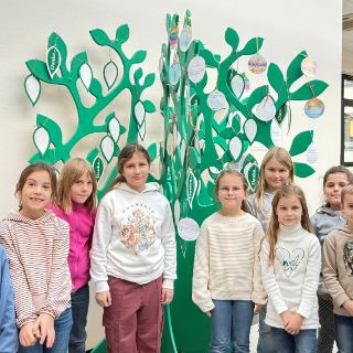 Freuen sich: die Kinder der zweiten Klasse vor dem „Danke-Baum“, Zweite Klasse der Worthschule zu Besuch in der Asklepios Harzklinik Goslar  Schüler:innen schmücken Danke-Baum mit selbst gestalteten Festtags-Botschaften •	Es sind Bilder, Worte der Wertschätzung für die Mitarbeitenden   