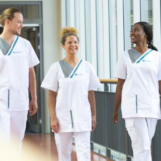 Das Bild zeigt 3 Mitarbeiter von Asklepios im Gespräch auf dem Flur. 