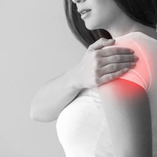 Das Motiv zeigt eine Frau mit Schulterschmerzen