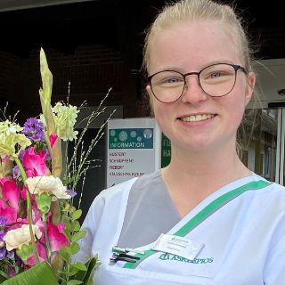 Das Motiv zeigt Pflegefachfrau Marlies Grumpelt, die ihre Ausbildung erfolgreich abgeschlossen hat, mit einem Blumenstrauß.